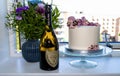 Birthdag cake decorated with pink flowers and a bottle of vintage French champagne Don Perignon and bouguet of flowers