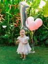 Birthday of baby girl with air balloons in outdoor garden. Happy child in dress Royalty Free Stock Photo