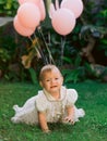 Birthday of baby girl with air balloons in outdoor garden. ÃÂ¡rying child in dress Royalty Free Stock Photo