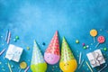 Birthday background with funny balloons in caps, gifts, confetti, candy and candles. Flat lay. Greeting card with copy space. Royalty Free Stock Photo