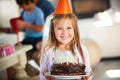 Birthday cake is the best kind of cake. Portrait of a happy little girl holding a birthday cake with her family in the Royalty Free Stock Photo