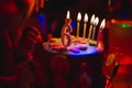 Birthday cake with burning candles and age 6 candle in the dark background with candies in decor Royalty Free Stock Photo