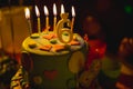 Birthday cake with burning candles and age 6 candle in the dark background with candies in decor Royalty Free Stock Photo