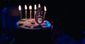 Birthday cake with burning candles and age 6 candle in the dark background with candies in decor