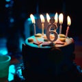Birthday cake with burning candles and age 6 candle in the dark background with candies in decor Royalty Free Stock Photo