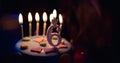 Birthday cake with burning candles and age 6 candle in the dark background with candies in decor Royalty Free Stock Photo