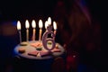 Birthday cake with burning candles and age 6 candle in the dark background with candies in decor Royalty Free Stock Photo