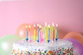 Birthday cake with burning candles and balloons on color background Royalty Free Stock Photo