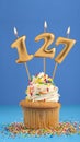 Birthday cake with candle number 127 - Blue background