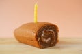 Birthday cake and a candle on top on a wooden board.