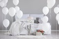 Birthday cake with candles in the middle of king size bed with grey bedding, real photo with copy space on the empty wall Royalty Free Stock Photo