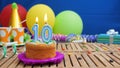 Birthday 10 cake with candles on rustic wooden table with background of colorful balloons, gifts, plastic cups and candies