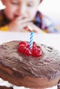 Birthday cake closeup, young kid and celebration candle with dessert at home with a child. Chocolate, cherry and candles Royalty Free Stock Photo