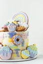 Birthday cake with colorful cream cheese frosting decorated with cookies. Gingerbread cookies in the shape of rainbow, cupcakes, Royalty Free Stock Photo