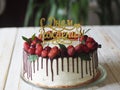 Birthday cake decorated with chocolate and red berries, top with strawberries and cherries on white cream Royalty Free Stock Photo