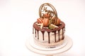 Birthday cake decorated with golden macaroons and chocolate pieces. Elegant naked cake topped by chocolate. Birthday party