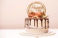 Birthday cake decorated with golden macaroons and chocolate pieces. Elegant naked cake topped by chocolate. Birthday party