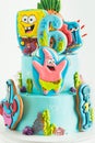 Birthday cake for a fan of SpongeBob SquarePants on white background. Nautical turquoise bunk cake with characters of animated Royalty Free Stock Photo