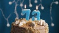 Birthday cake with 73 number candle on blue backgraund. Candles blow out