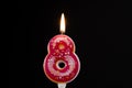 Birthday cake number 8 pink donut candles burning by lighter, black background