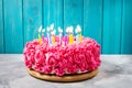 Birthday cake with pink cream and burning candles on blue wooden background Royalty Free Stock Photo