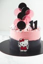 Birthday cake with pink cream cheese frosting and lollipops on top. Cake for a girl on the white background. Hello Kitty