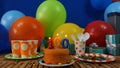 Birthday 100 cake on rustic wooden table with background of colorful balloons, gifts, plastic cups, plastic plate Royalty Free Stock Photo