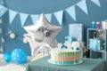 Birthday cake on table in room decorated for party Royalty Free Stock Photo