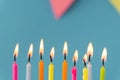 Birthday cake with white cream cheese frosting decorated with multicolored lit candles on a blue background. Happy Birthday Royalty Free Stock Photo