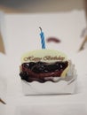 Birthday candle lit on the cake Blueberry Cheese Pie with Whipped Cream in white paper box