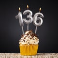 Birthday candle number 136 - Anniversary cupcake on black background