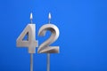 Birthday candle number 42 - Celebration card on blue background