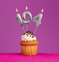 Birthday candle number 104 with cupcake on violet background Royalty Free Stock Photo