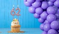 Birthday card with number 62 candle, cupcake and balloons