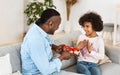 Birthday celebration. African american granddad giving gift box to his little granddaughter at home Royalty Free Stock Photo