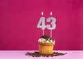 Birthday celebration with candle number 43 - Chocolate cupcake on pink background