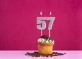 Birthday celebration with candle number 57 - Chocolate cupcake on pink background