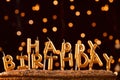 Minimalistic background with golden candles without fire letters in cake close up. Garland of yellow bokeh circles at