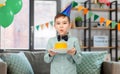 boy in party hat blowing candle on birthday cake Royalty Free Stock Photo