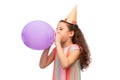 little girl in birthday party hat blowing balloon Royalty Free Stock Photo