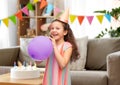 happy girl in birthday party hat blowing balloon Royalty Free Stock Photo