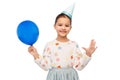 happy girl in birthday party hat blowing balloon Royalty Free Stock Photo