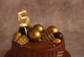 Birthday chocolate cake with gold balls and a candle with the number 5 on a beige background Royalty Free Stock Photo