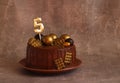 Birthday chocolate cake with gold balls and a candle with the number 5 on a beige background Royalty Free Stock Photo