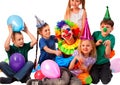 Birthday clown playing children. Kid wearing party hat hold balloons .