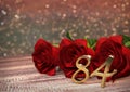 Birthday concept with red roses on wooden desk. eighty-fourth. 84rd. 3D render