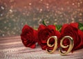 Birthday concept with red roses on wooden desk. ninety-nineth. 99th. 3D render