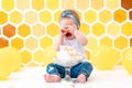 Birthday. A crying dirty toddler girl is sitting next to a broken cake. In the background is a pattern of yellow