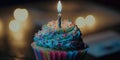 birthday cupcake with candle closeup. Blue frosting with rainbow sprinkles. Colorful baked goods. Happy birthday