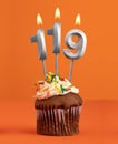 Birthday cupcake with number 119 candle - Orange color background